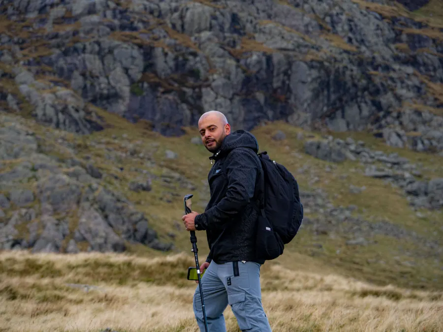 Man with a backpack and trekking pole hiking on a rocky mountain slope