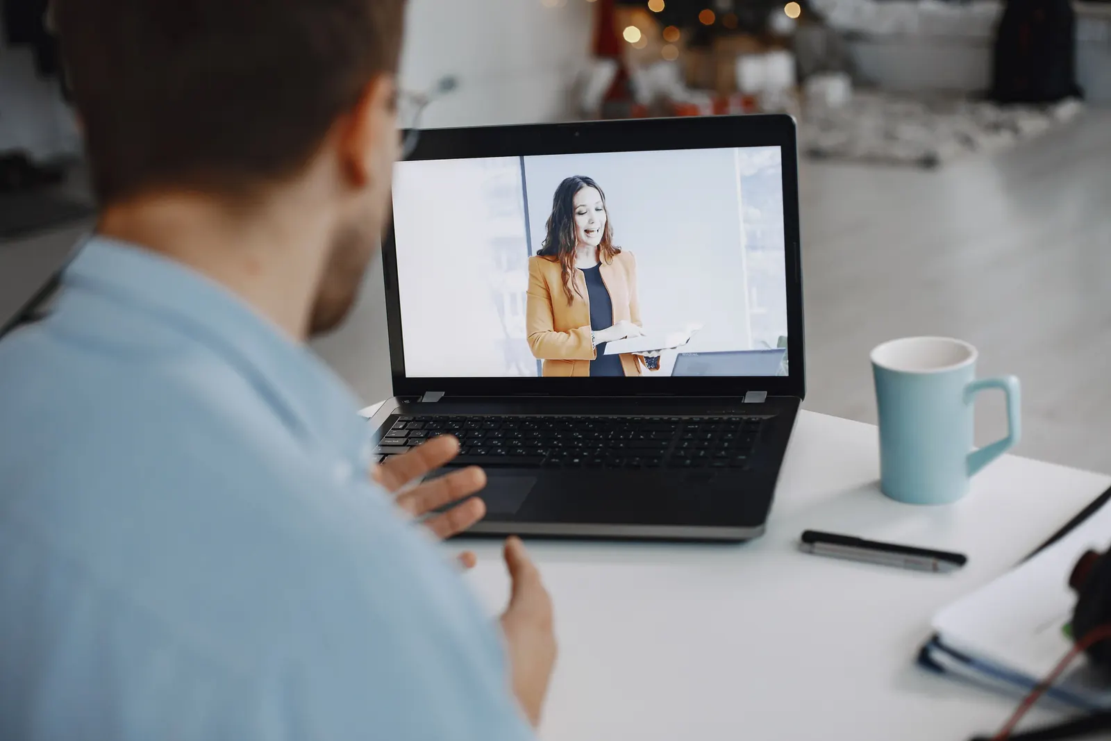 Man seen from behind talking with a clinician on a laptop video call