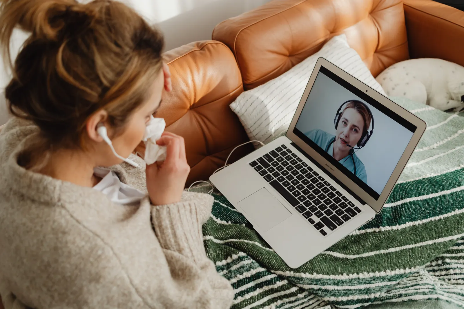 Woman on a sofa having an online medical consultation on her laptop